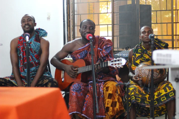 Three musicians in traditional cloth play guitar and a shekere at the first Innovation Clinic, iSpace, Accra