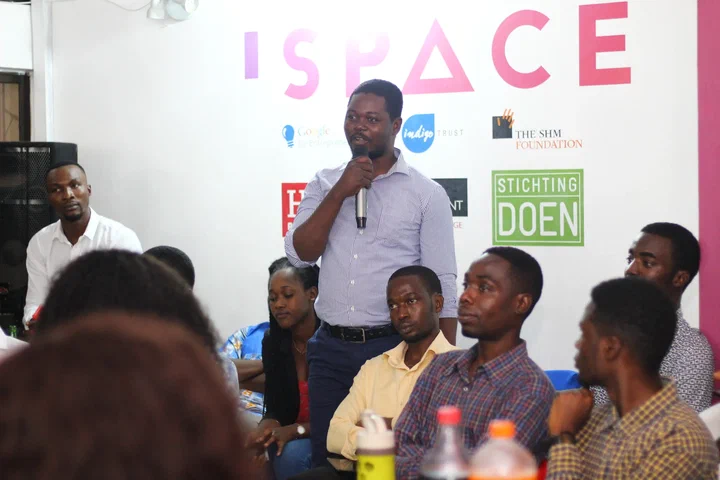 Peter Awin of CowTribe speaks into a microphone to seated participants at iSpace, Accra