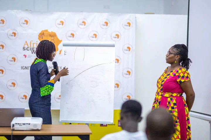 A Science Cafe speaker presents at a flip chart in front of an Africa Science Week banner